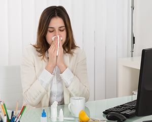 Woman blowing nose in an office with dirty air ducts and ventilation